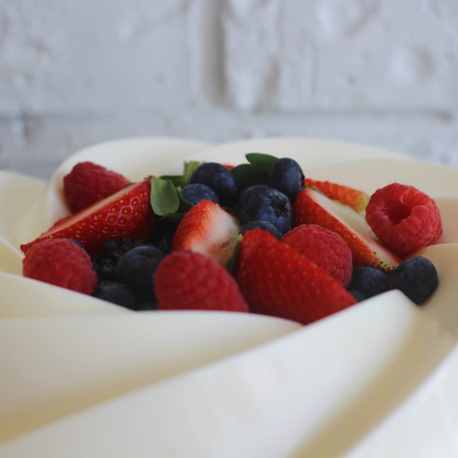 Pastel cubierto de crema con fresas, frambuesas y moras